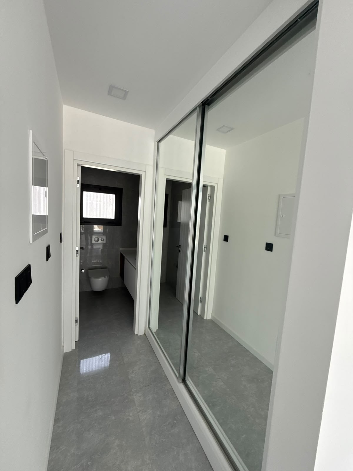 Hallway with a mirrored sliding wardrobe and a bathroom view, in the second unit of the apartment