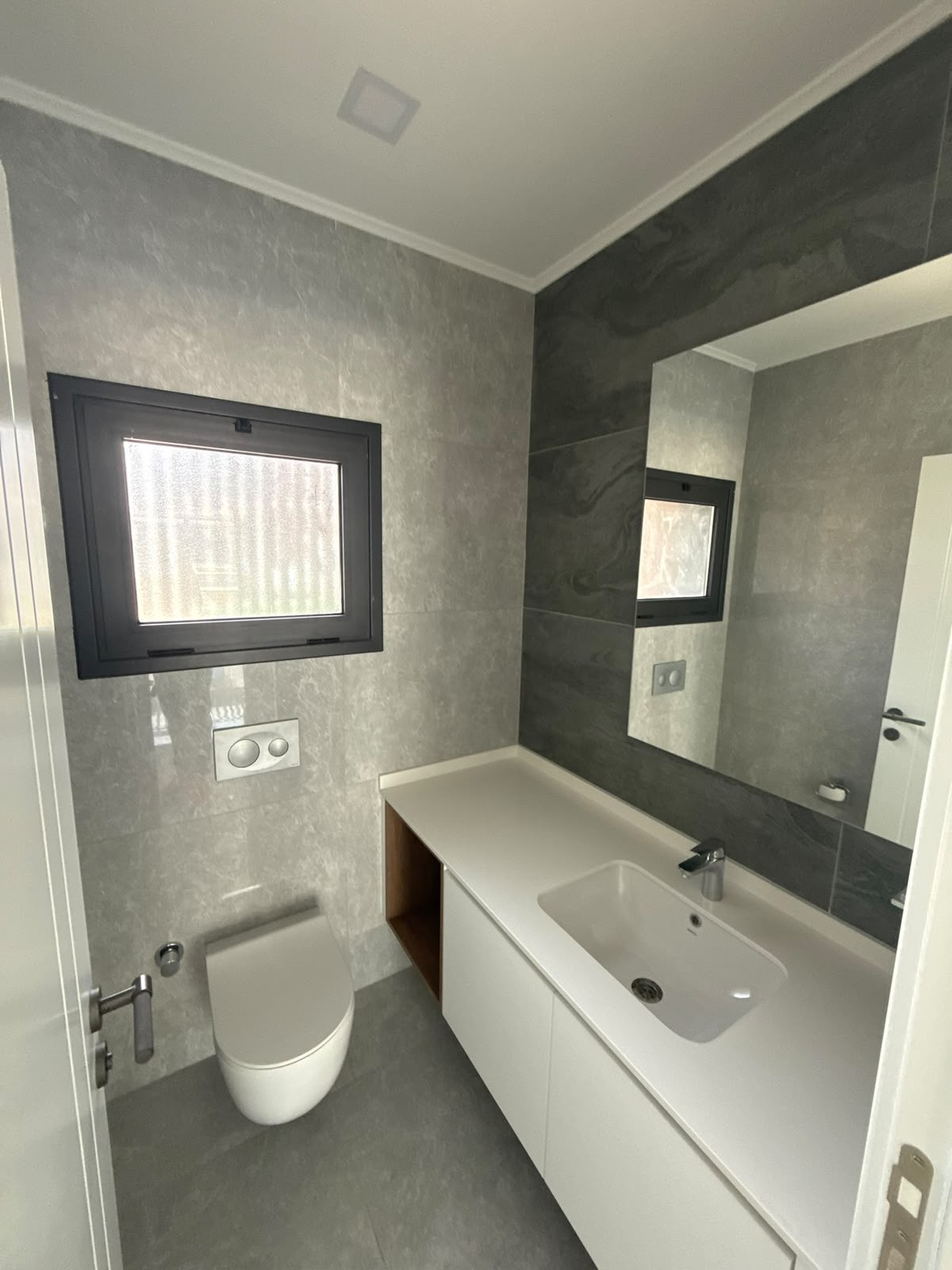 Bathroom: toilet, window, and a sink with a countertop