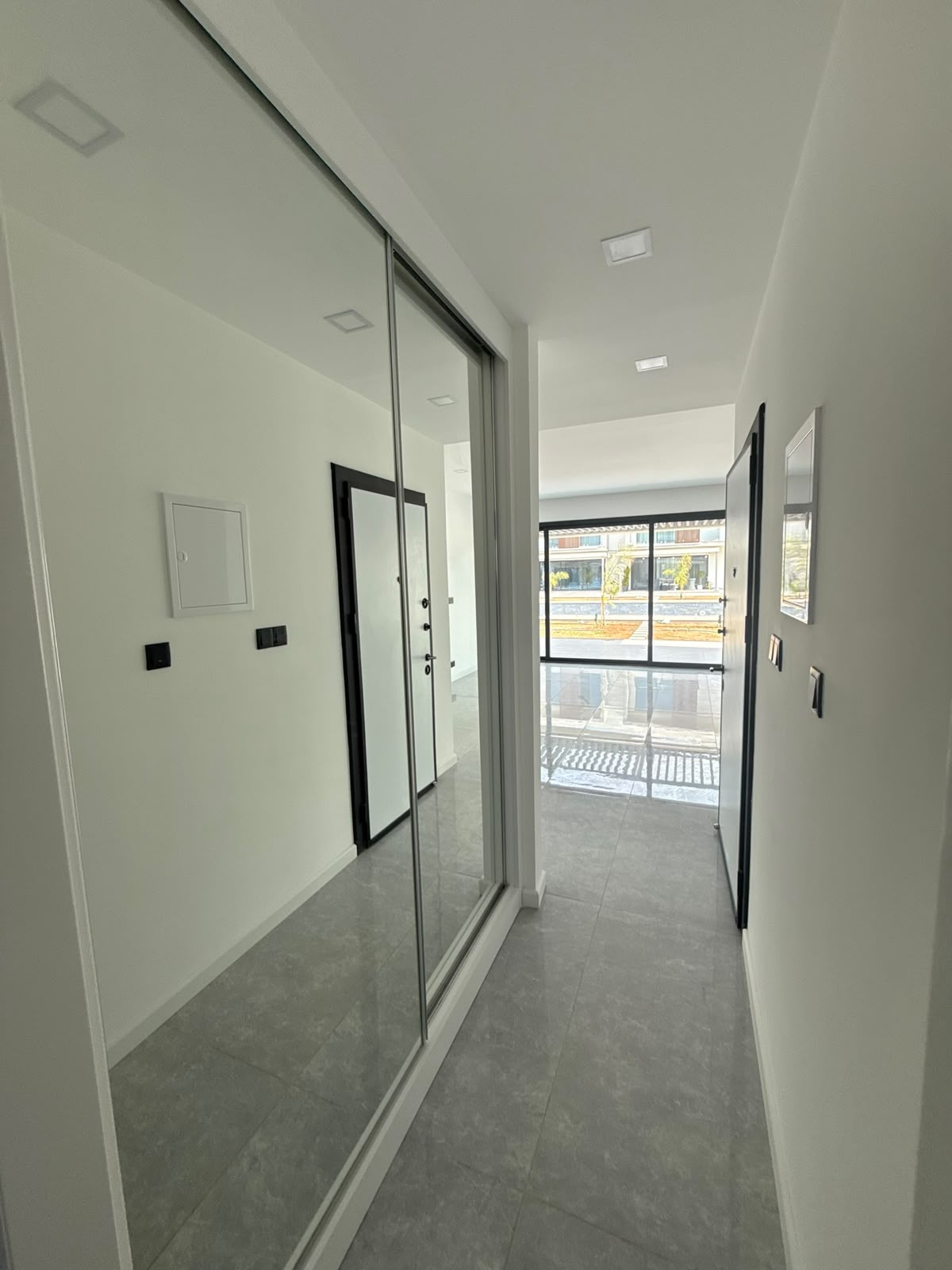 Apartment hallway with a mirrored wardrobe and a view of the open front door and terrace