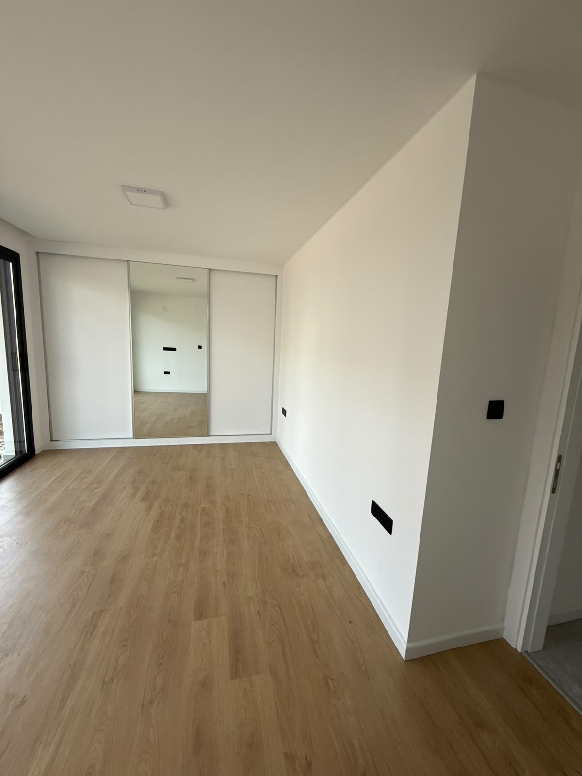 Bedroom with a built-in mirrored sliding wardrobe, laminate flooring