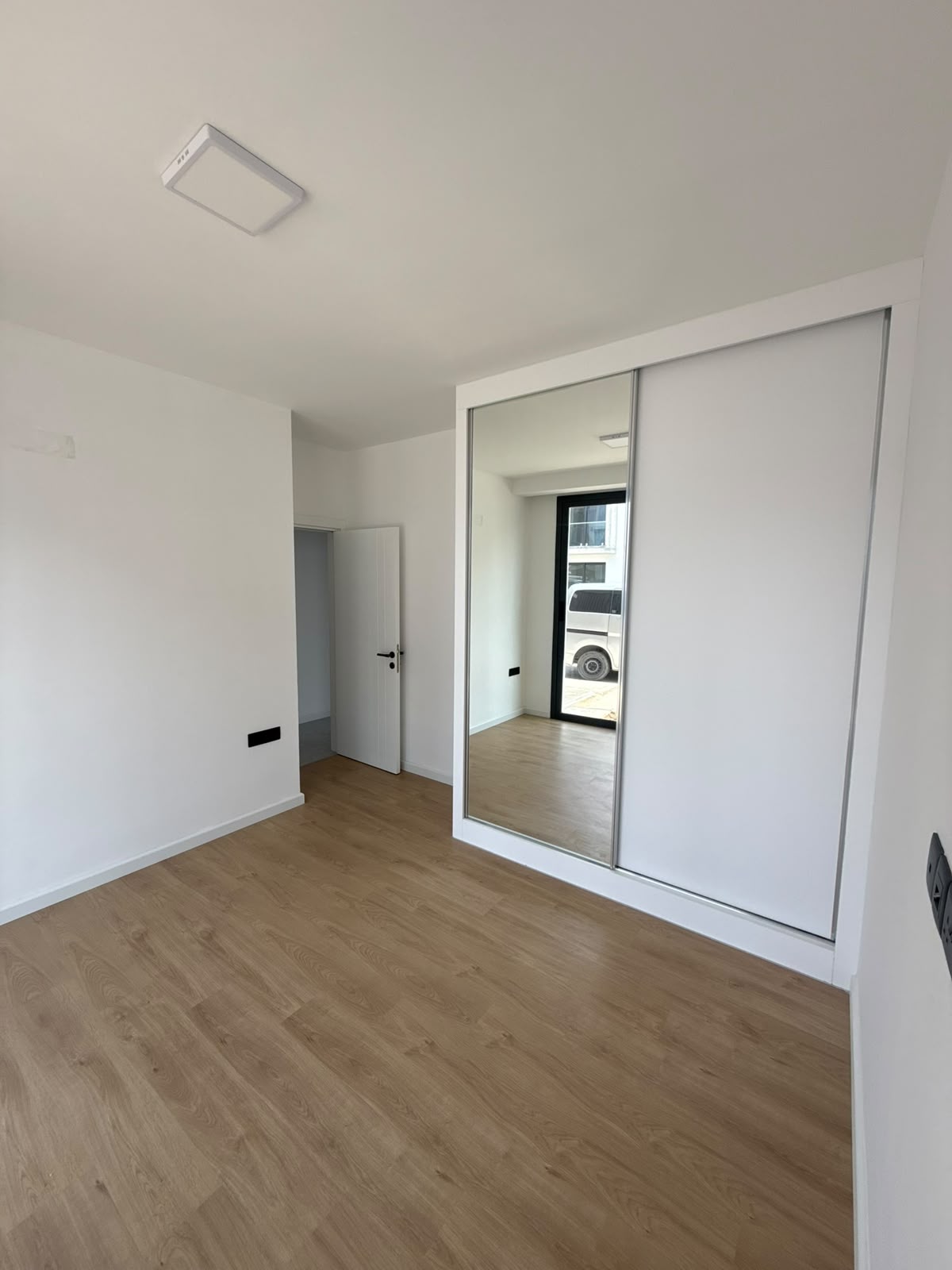 Bedroom with a sliding wardrobe, window overlooking the parking area
