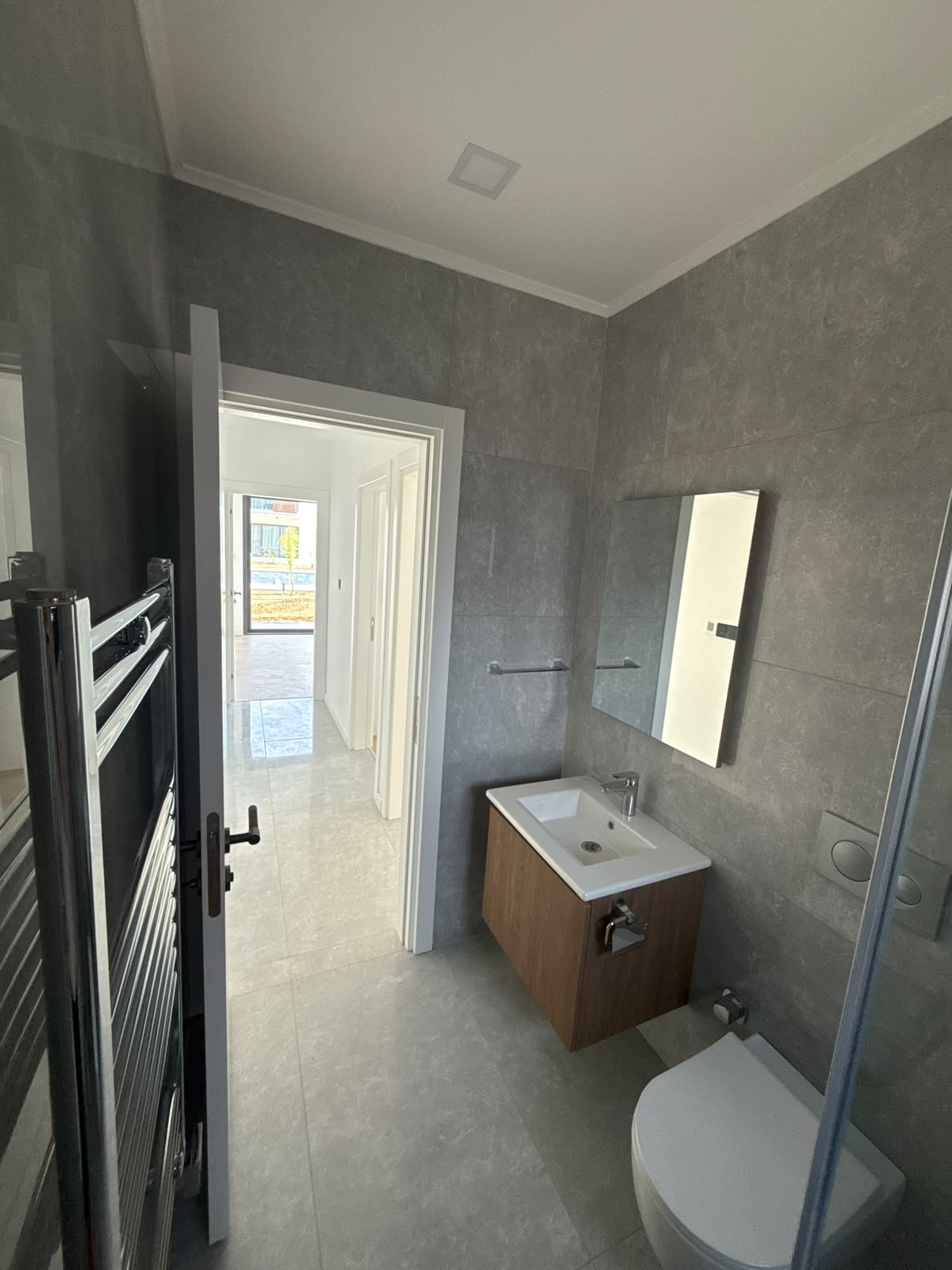 Bathroom with a shower cabin, toilet, and a view into the hallway