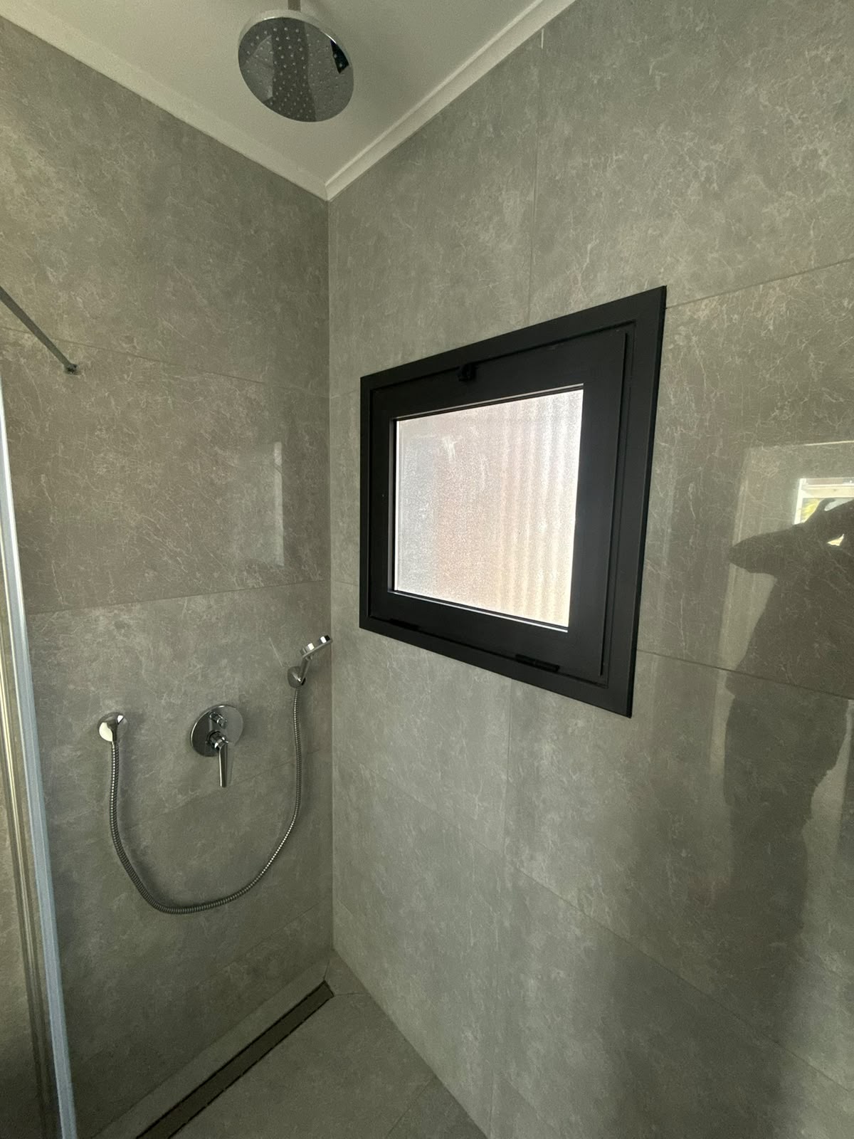 Shower area with an overhead rain shower and a window