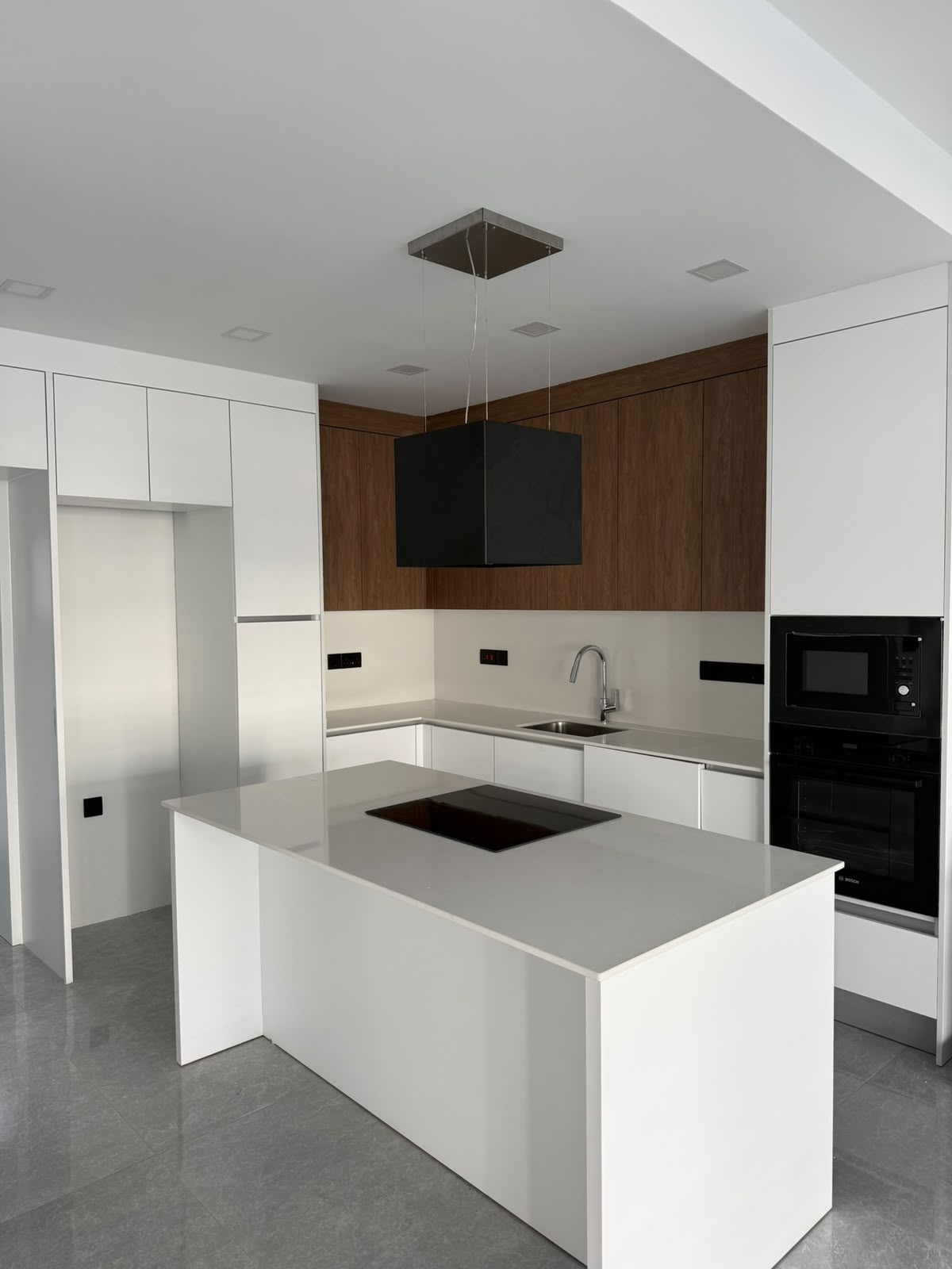 Kitchen: dark wood cabinets, extractor hood, oven, microwave, island with a cooktop