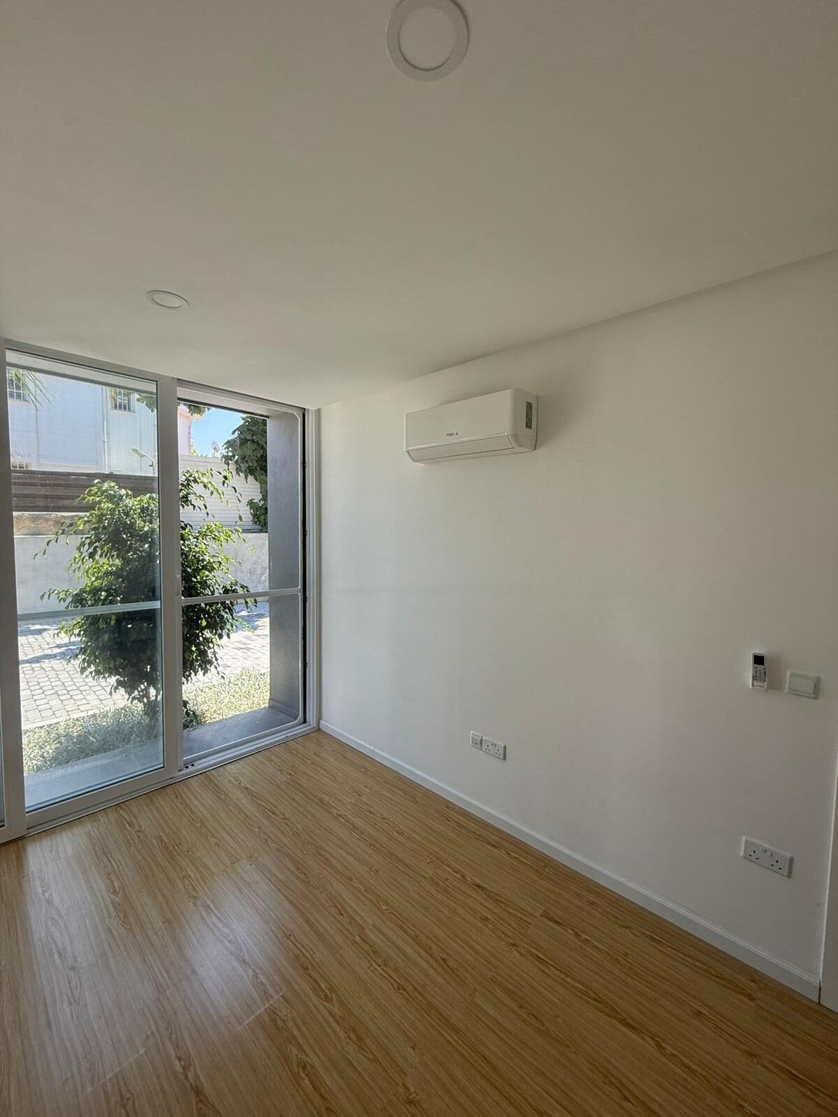 Bedroom with laminate flooring and a wall-mounted air conditioner
