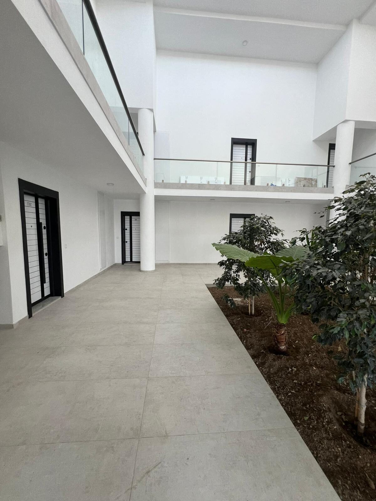 Ground-floor corridor of the complex with a landscaped courtyard and apartment doors