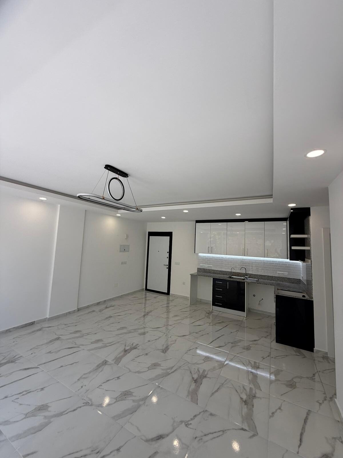 Kitchen-living area: white glossy cabinets, black fronts, built-in appliances