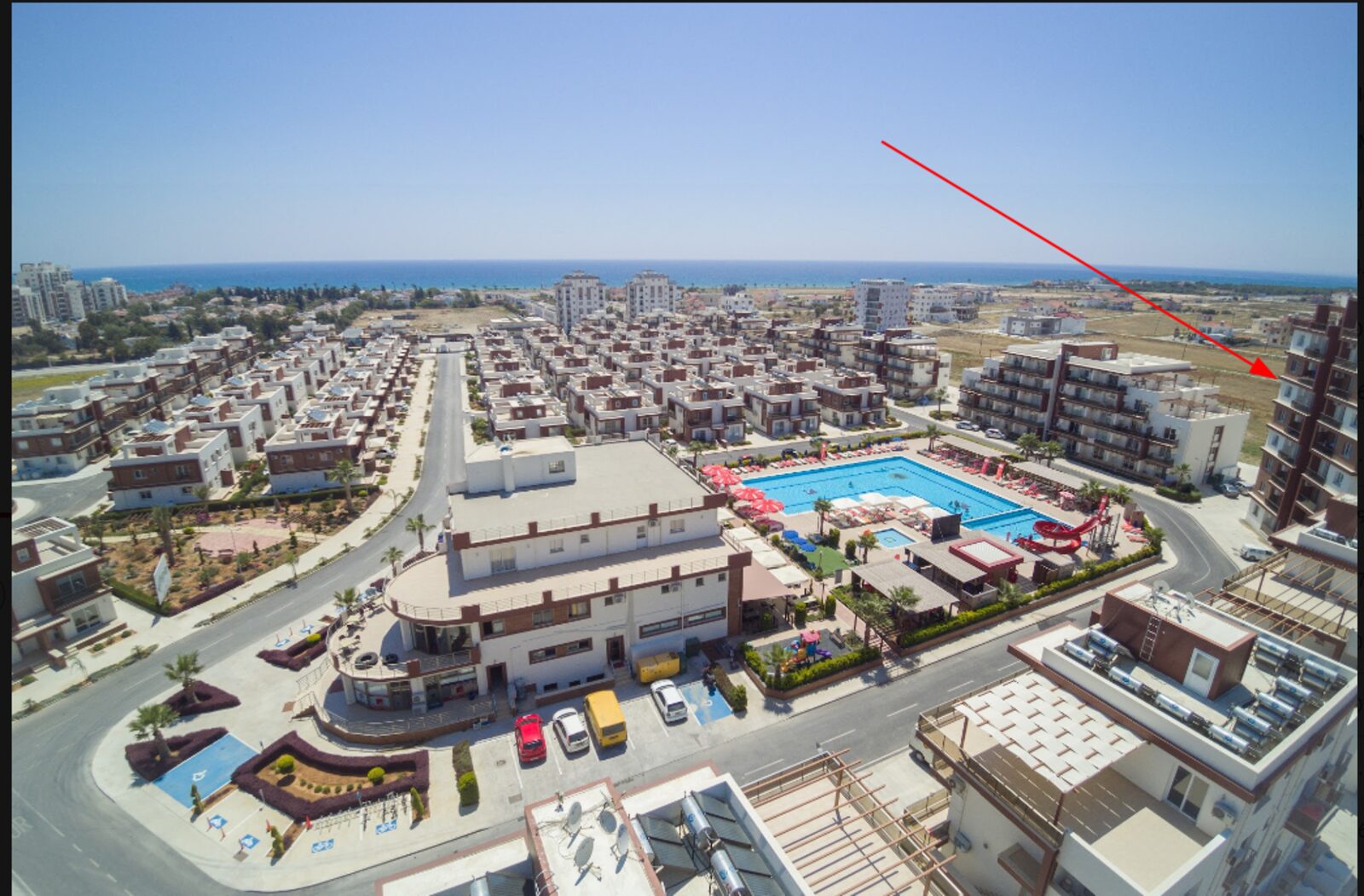 Aerial view of the complex with block River 1 marked: the central pool, the restaurant building and the sea beyond