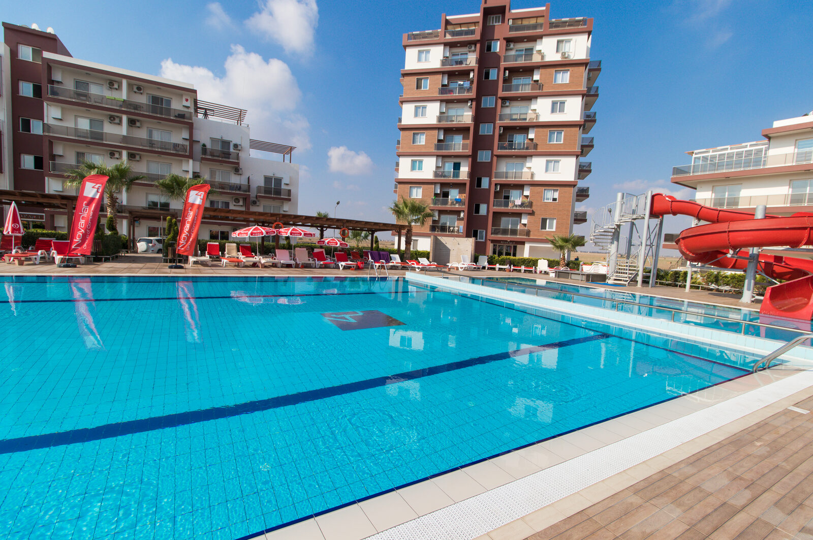 The complex's central pool with its water slide and sun loungers, block River Apt 1 behind