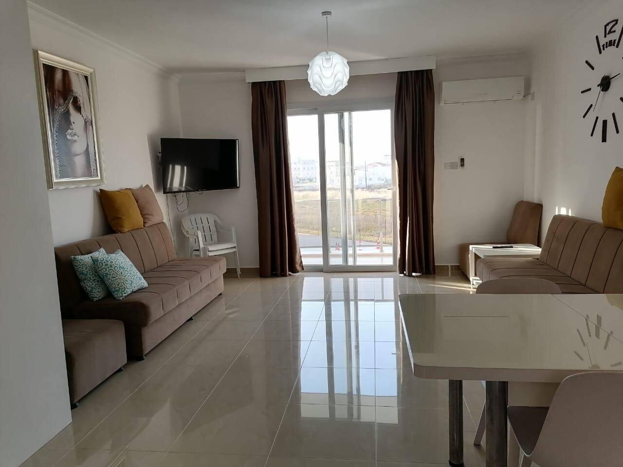 Living room with a wall-mounted TV, sofas and the door out to the balcony