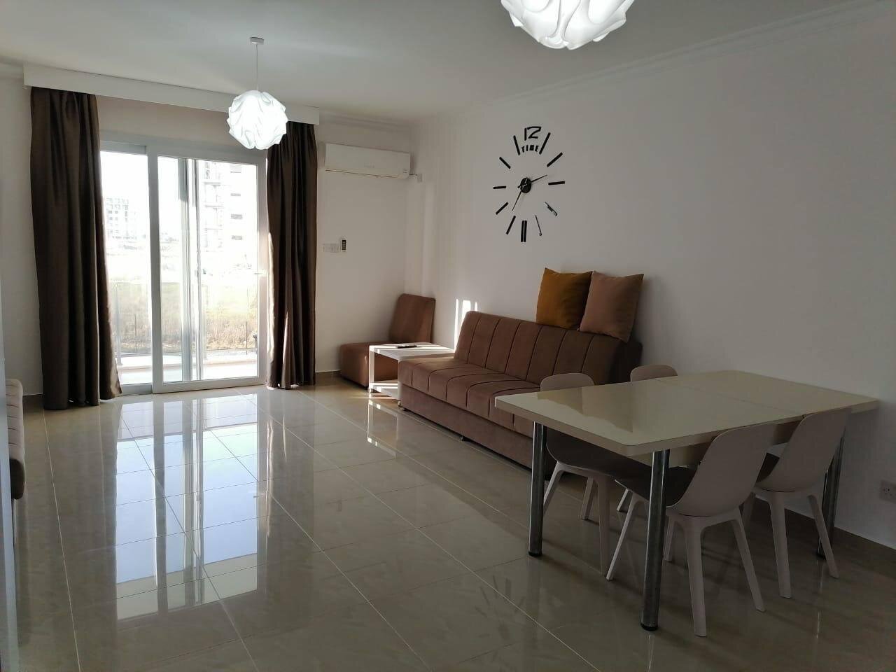 Living room: balcony door with heavy curtains, air conditioner and the dining area