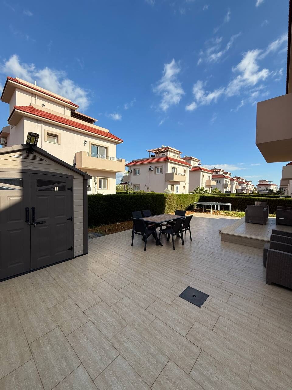 Terrace in front of the house: dining table with chairs and the barbecue area