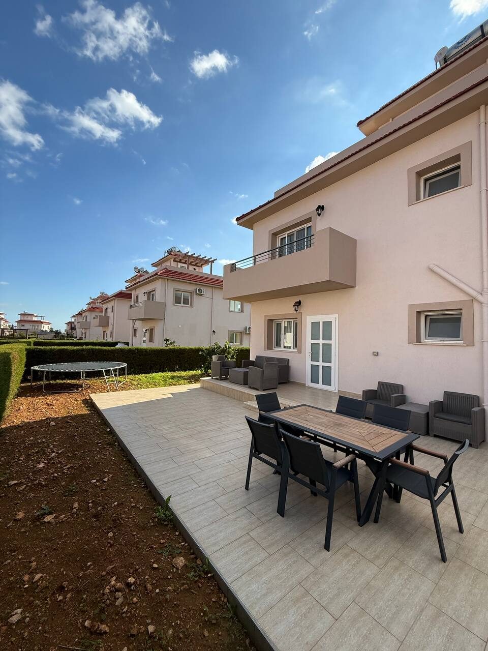 Lawn and terrace with a dining set beside the villa