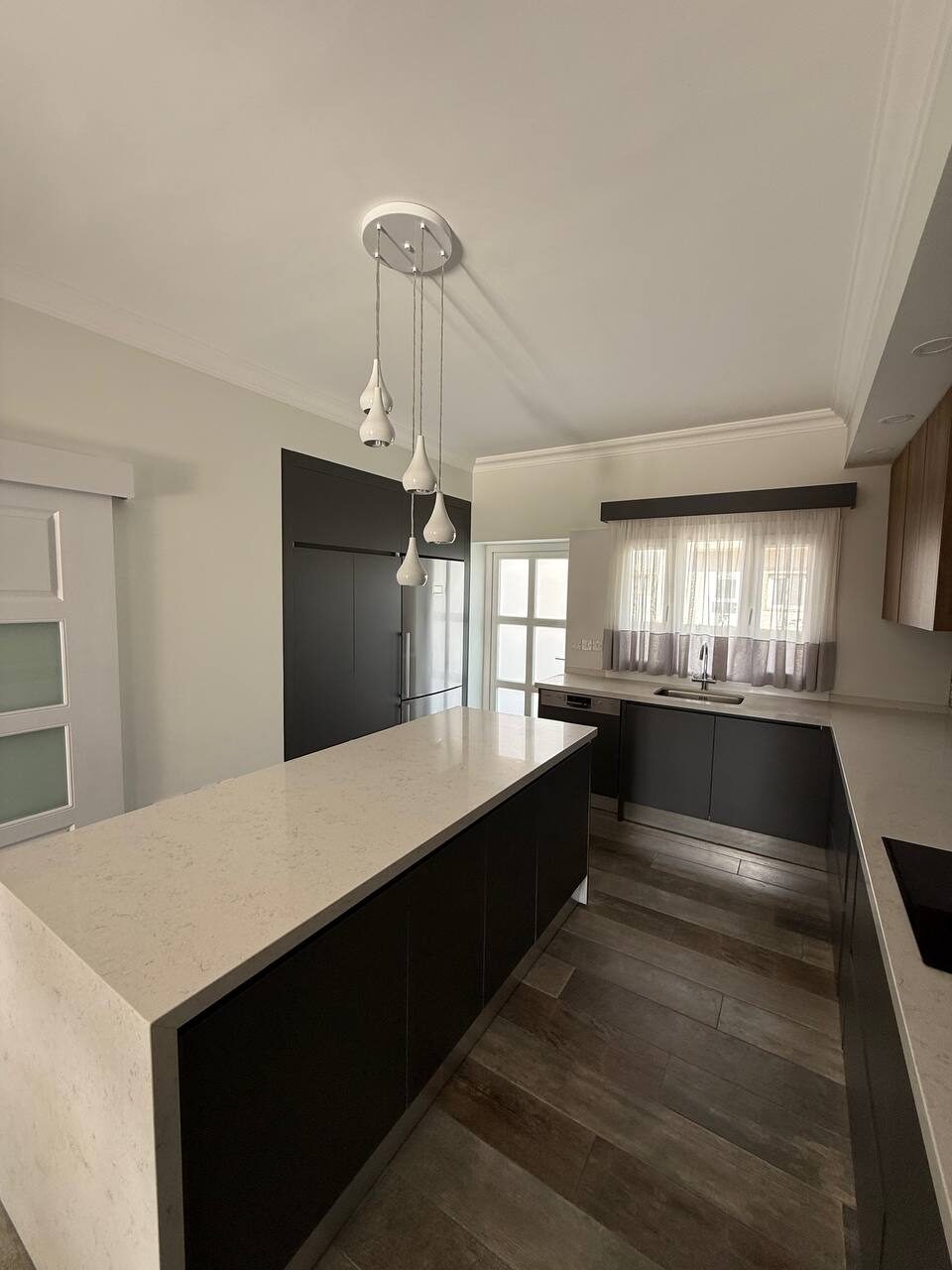 Full length of the kitchen: island, dark fronts, built-in appliances