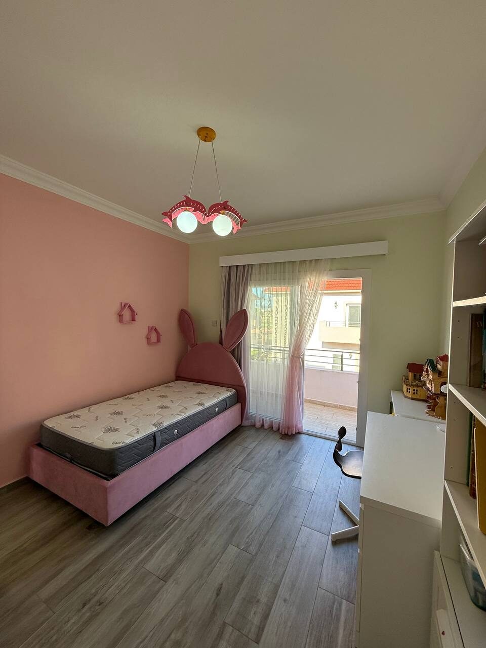 Child's room with a bed, shelves and a door onto the balcony
