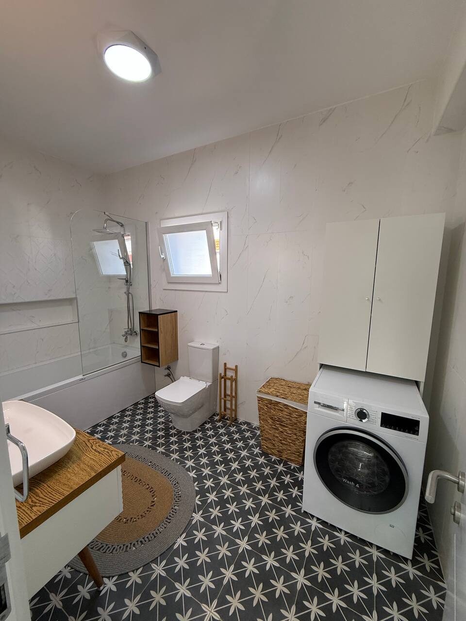 Bathroom with a washing machine and patterned floor