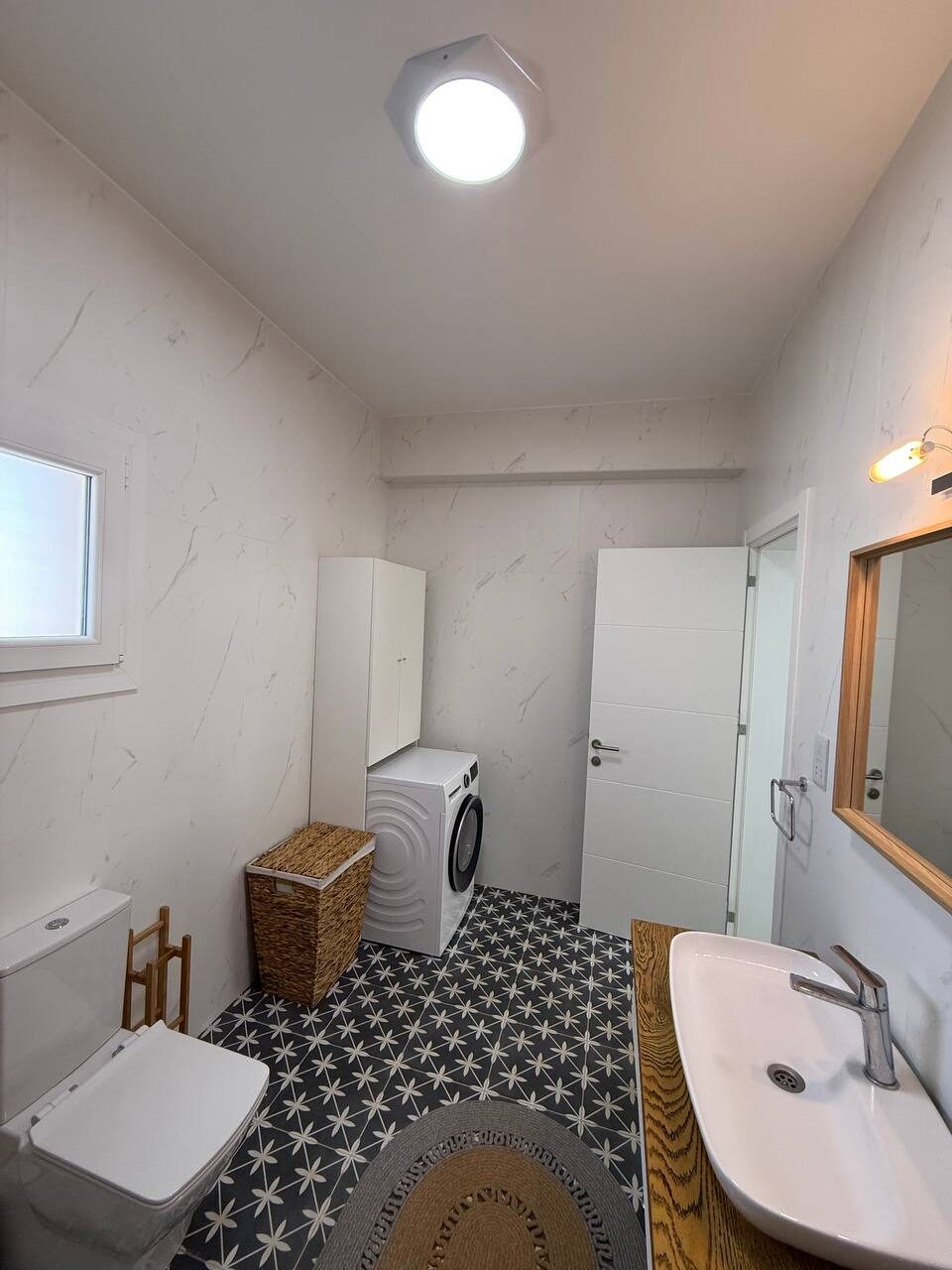 Second bathroom with a washing machine and laundry basket